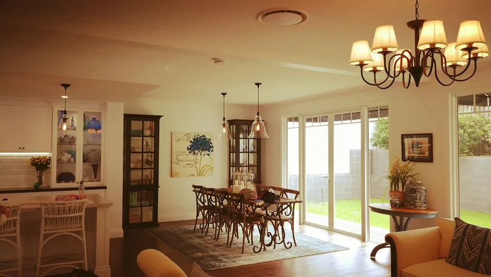 Open dining and living room lit by a chandelier and pendant lights
